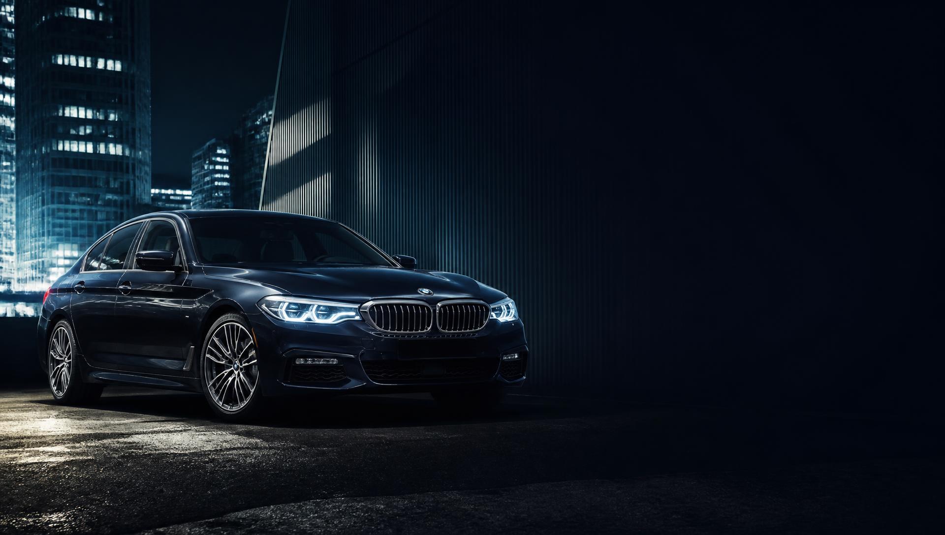 سيارة BMW فاخرة داكنة في مدينة ليلاً